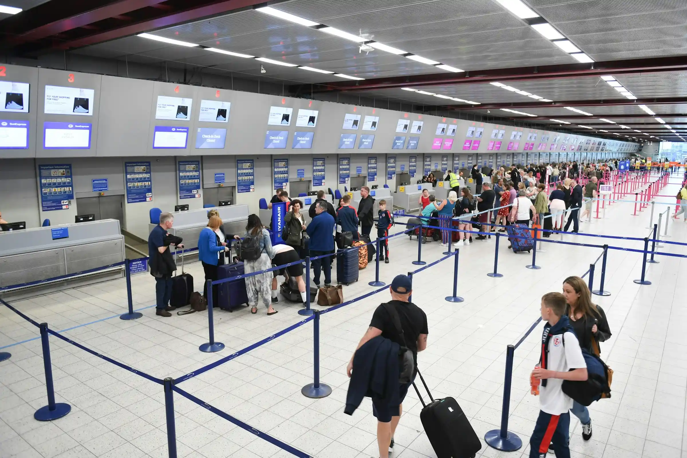 Travellers queuing with luggage at a busy airport check-in hall