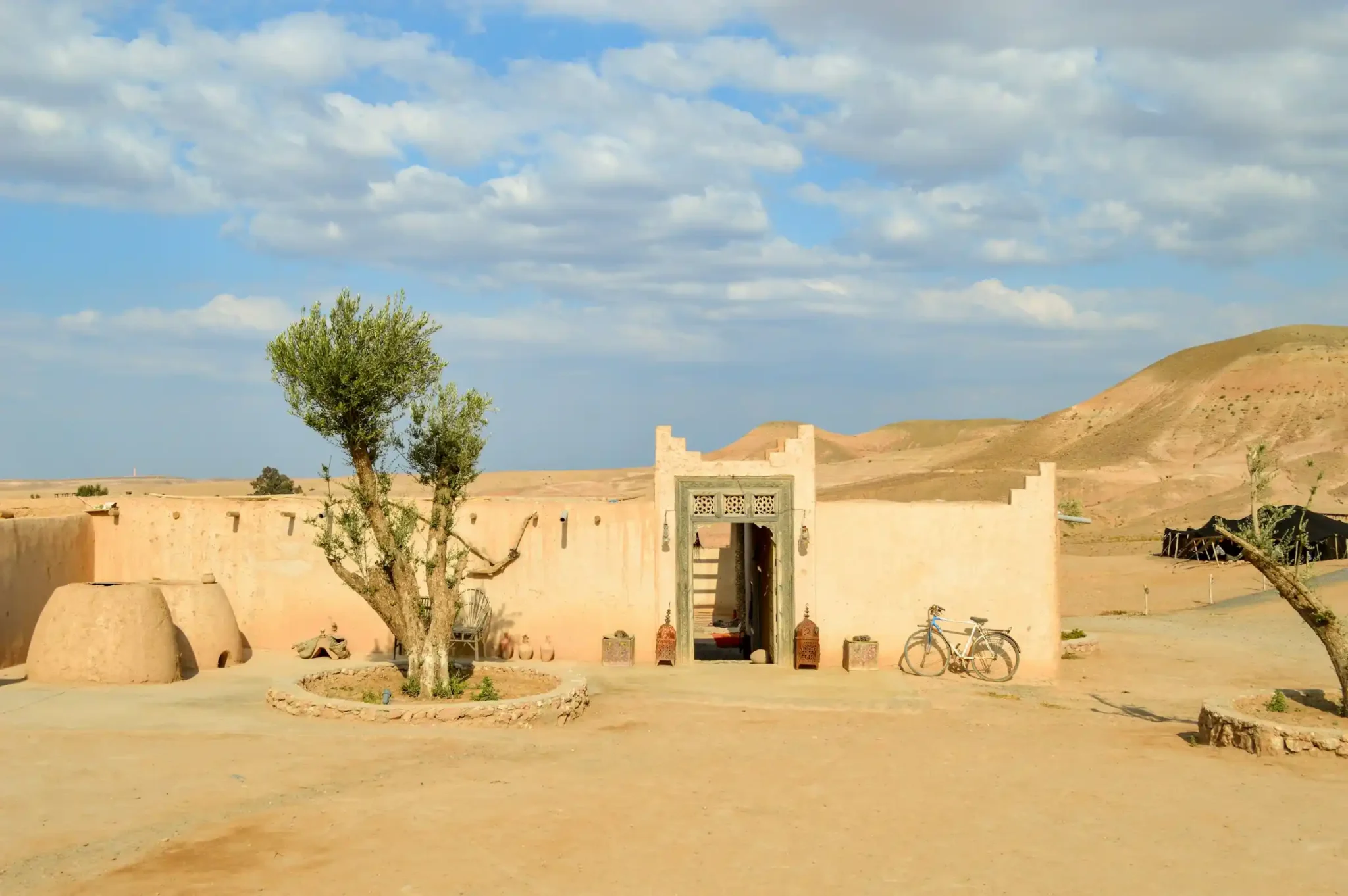 Agafay Desert rocky landscape with luxury camp tents and the Atlas Mountains in the background
