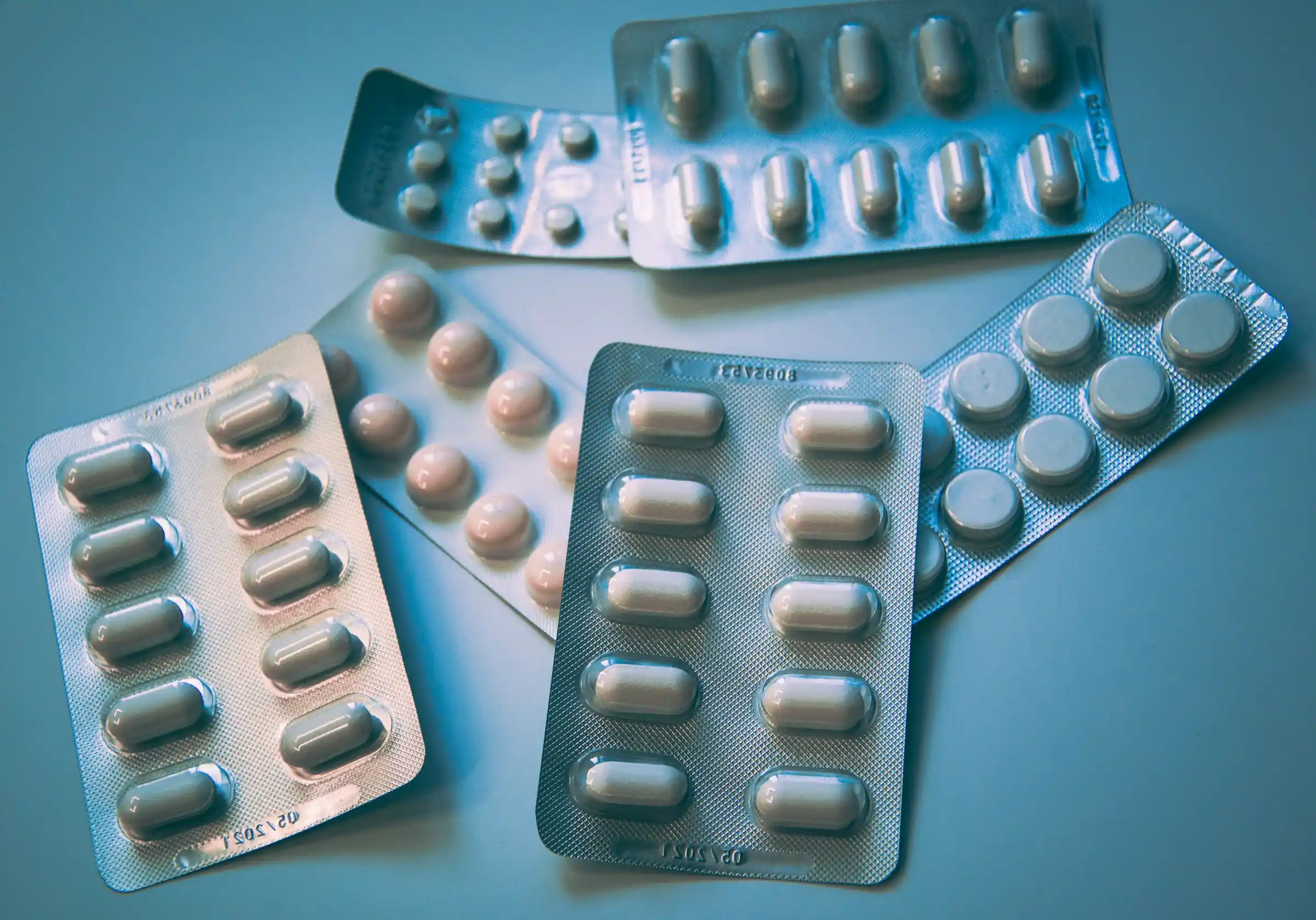 Blister packs of tablets and capsules on a blue surface