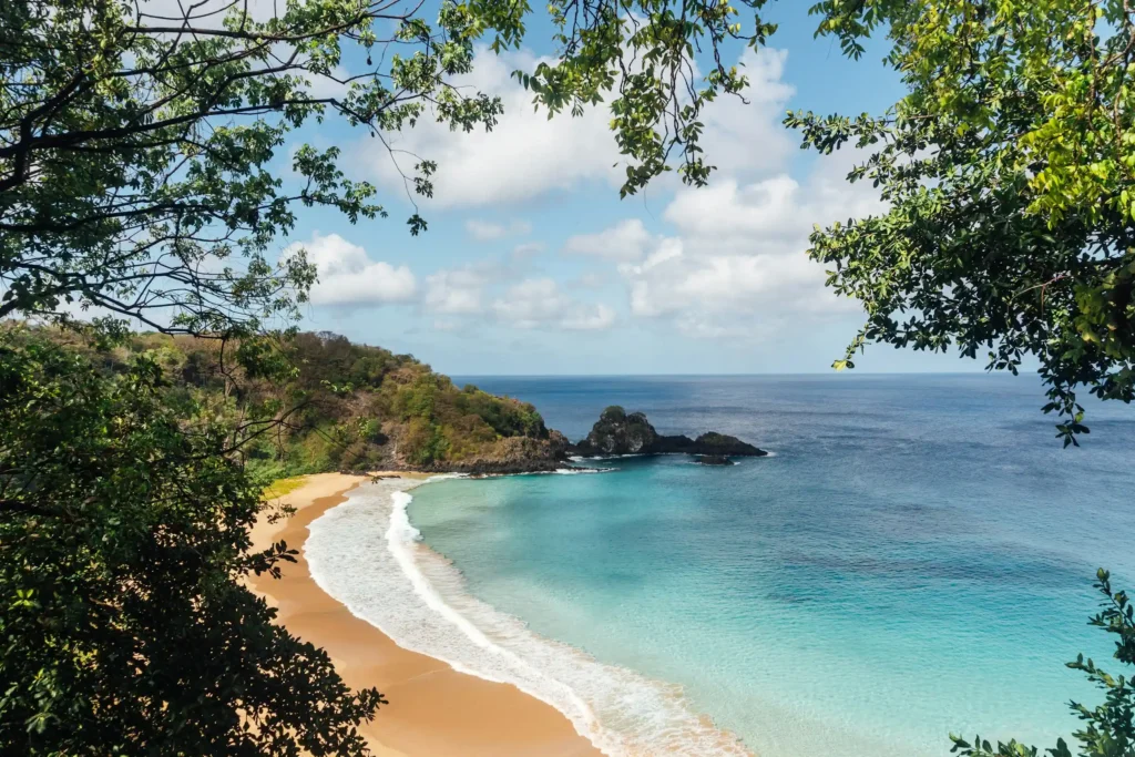 The curved turquoise bay and golden sand of Baía do Sancho seen from the clifftop, Fernando de Noronha, Brazil