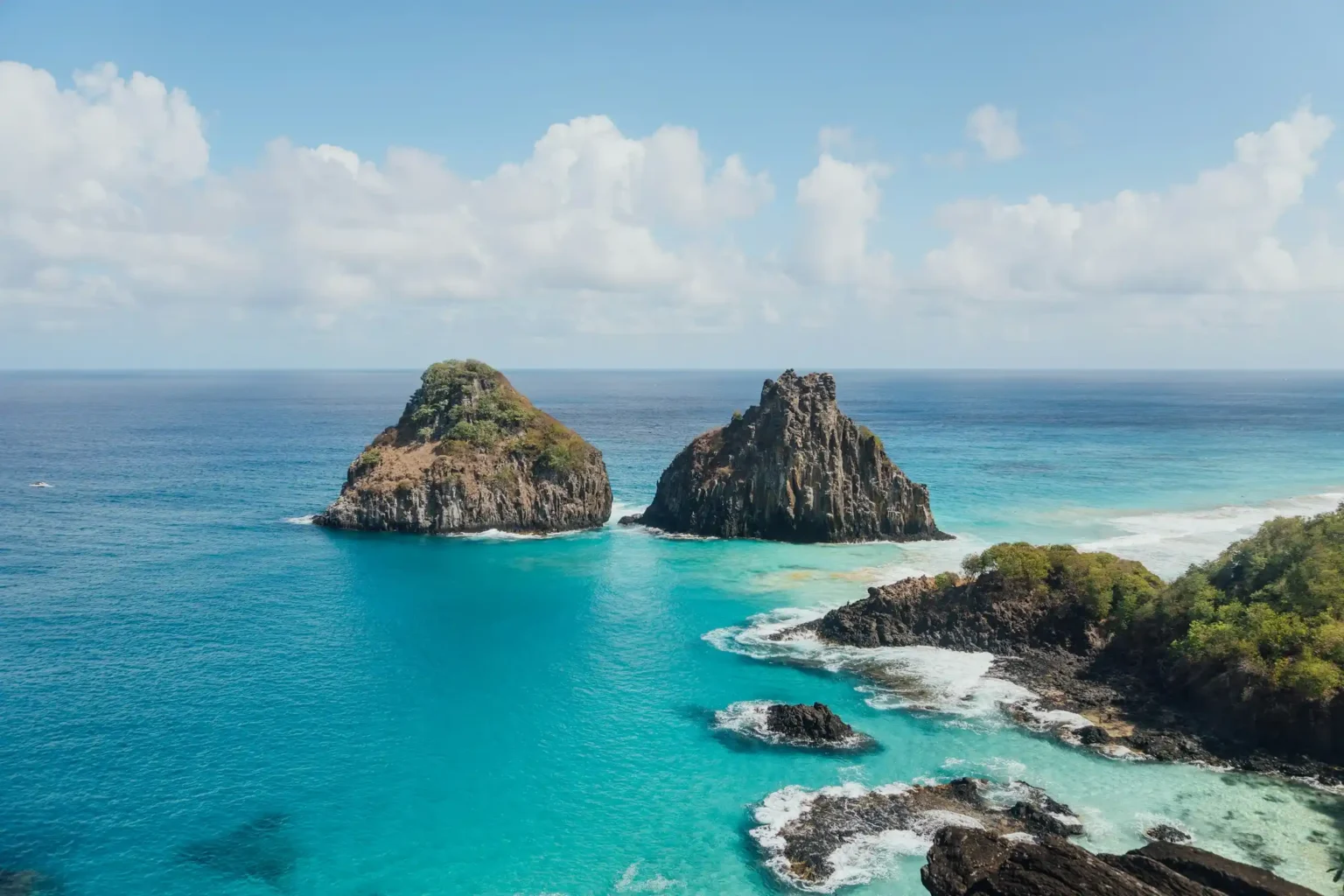 The twin Dois Irmãos rocks rising from turquoise water beside Baía dos Porcos, Fernando de Noronha
