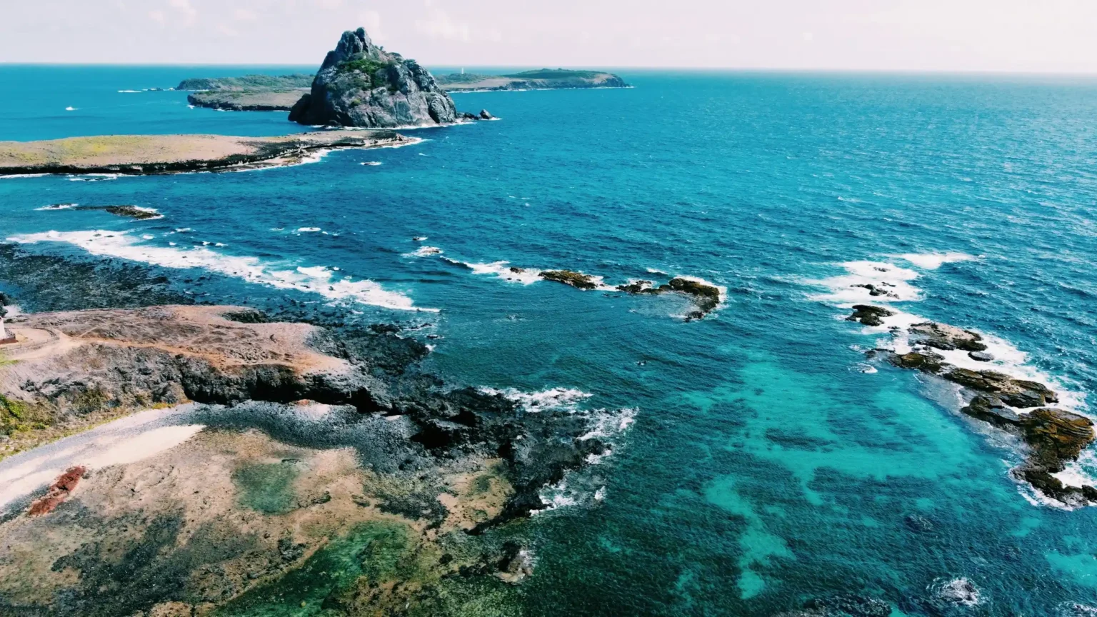 Aerial view of Morro do Pico and the reef-fringed coast of Fernando de Noronha, Brazil