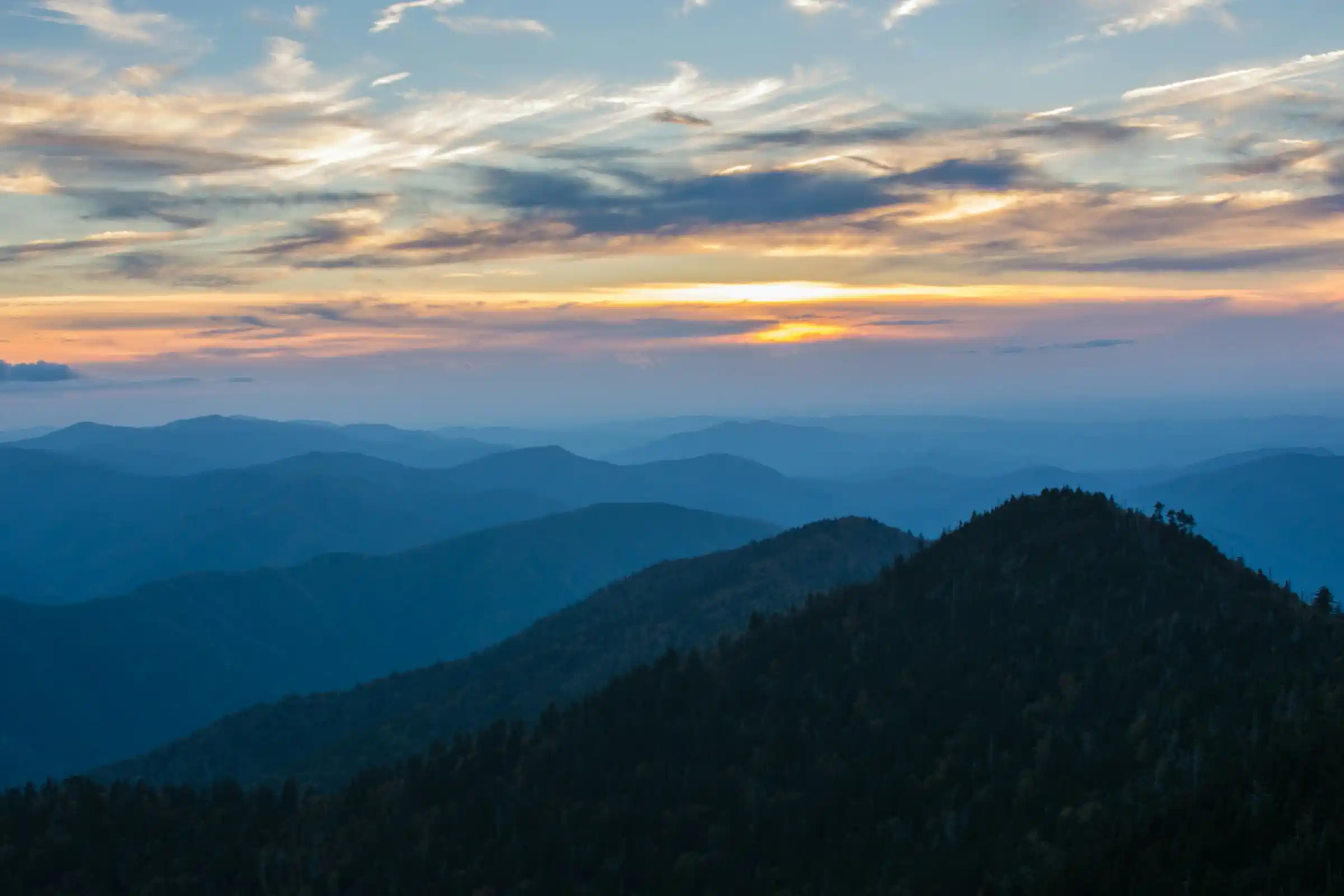 Sunset light painting the layered blue ridges of the Great Smoky Mountains