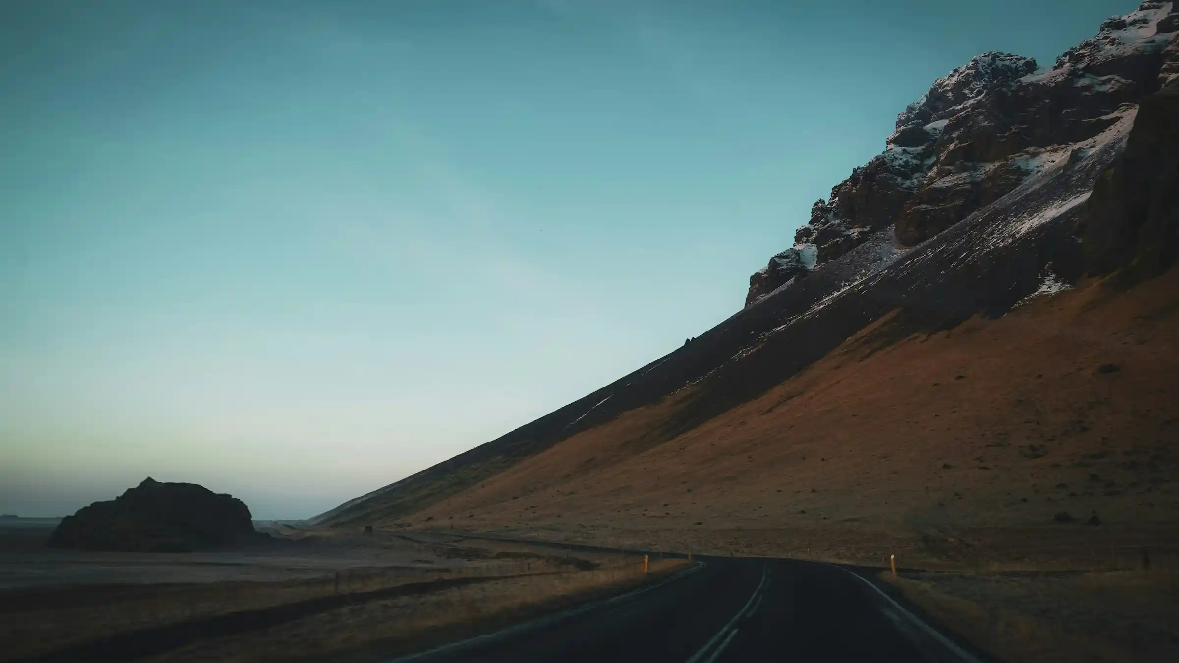 Iceland Ring Road winding through dramatic volcanic landscape with snow-capped mountains