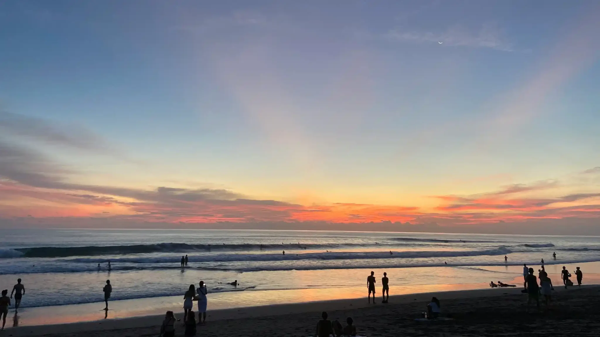 Surfers and visitors enjoying Kuta Beach Bali at sunset