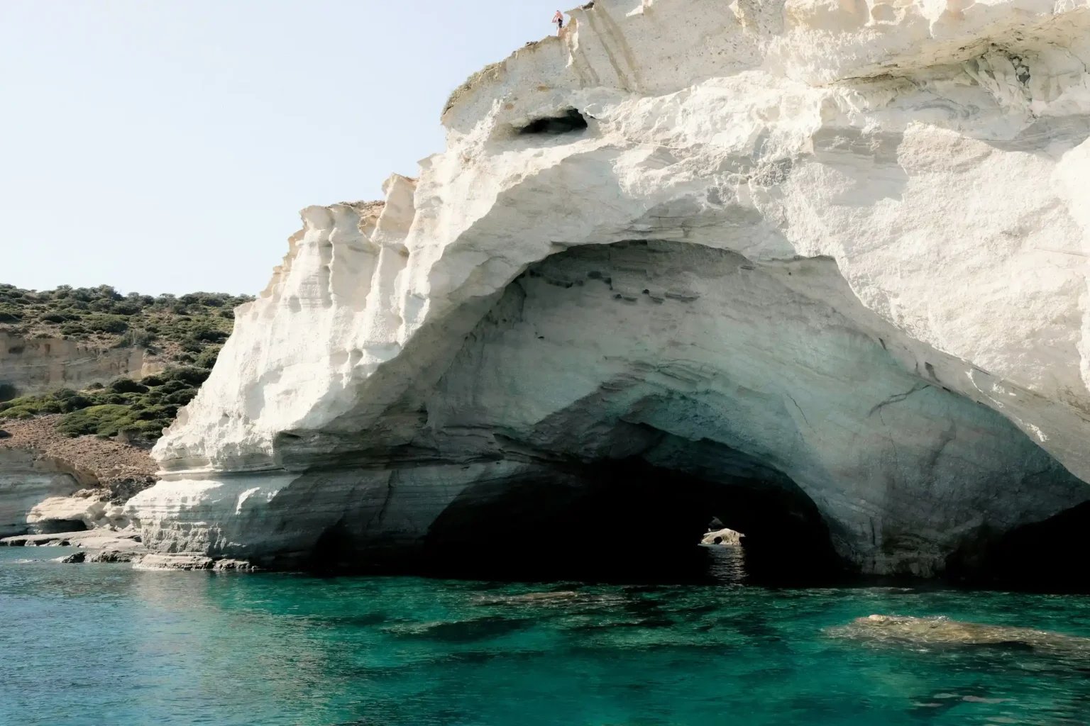 A white sea cave and cliff rising from turquoise water at Kleftiko, Milos