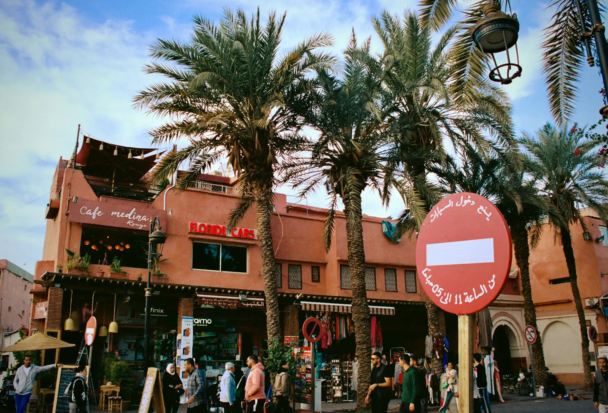Street scene in a Moroccan medina with locals walking past colorful market stalls