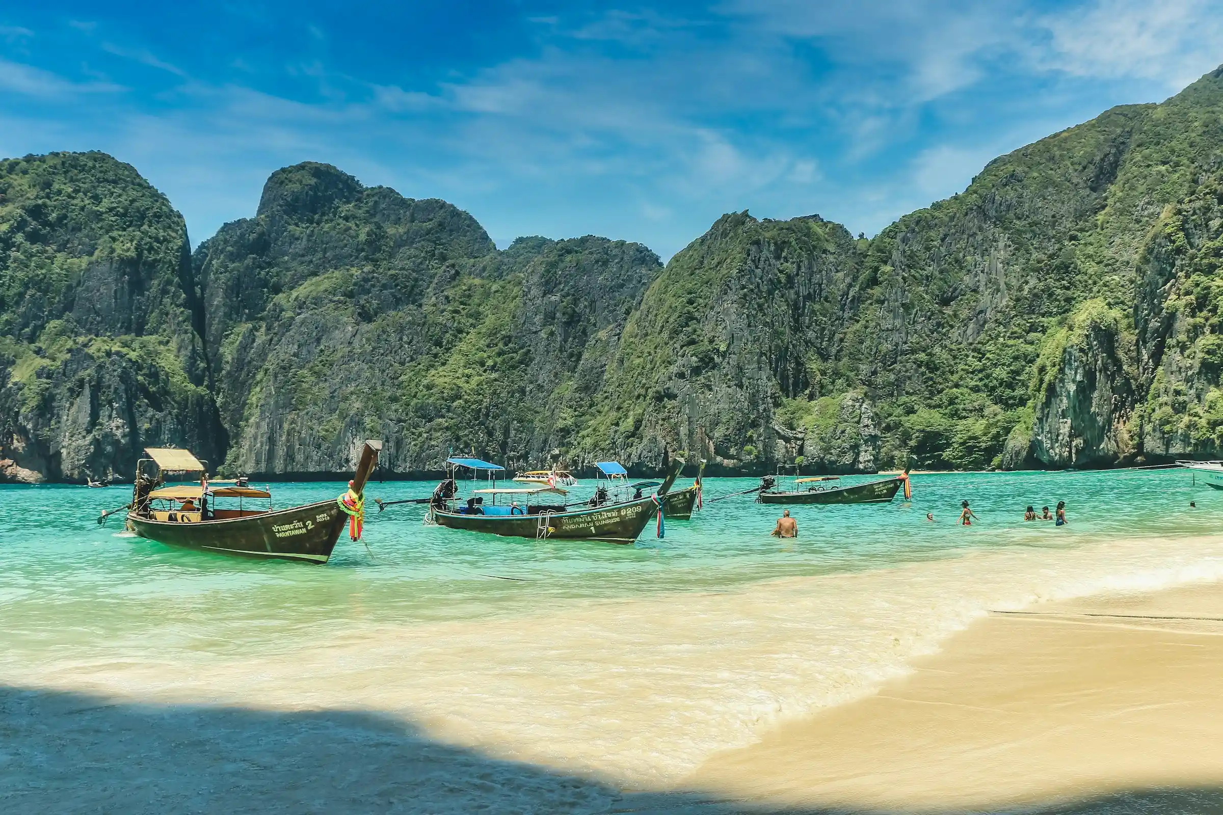 Longtail boats and towering limestone cliffs at Maya Bay on Phi Phi Leh