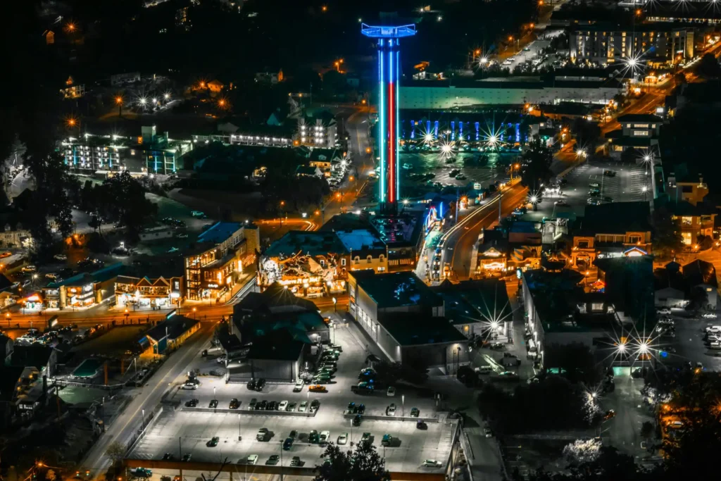 Aerial night view of downtown Gatlinburg with the illuminated Space Needle tower and the lit-up Parkway
