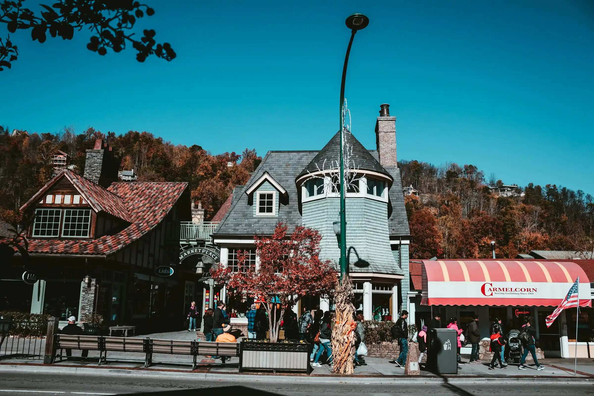Downtown Gatlinburg Parkway with shops, a candy store and visitors walking below autumn hillsides