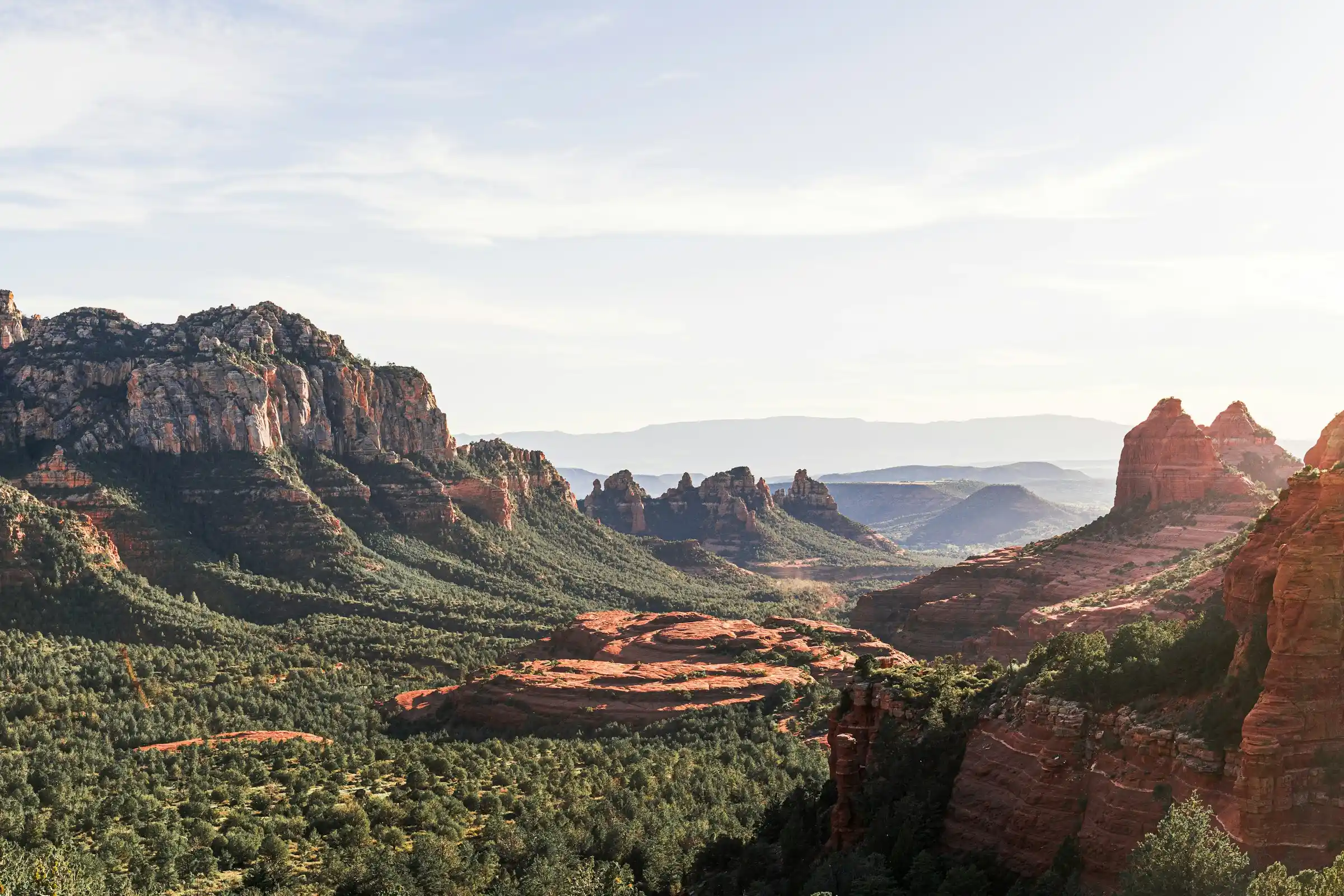 Layered red rock canyon and green valley seen from a scenic overlook near Sedona