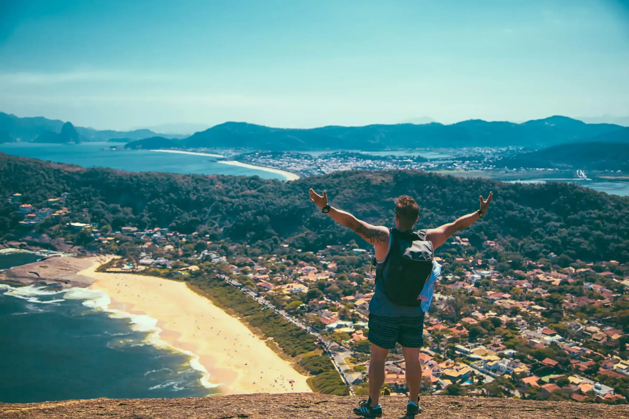 Solo traveler overlooking a coastal town from a hilltop viewpoint