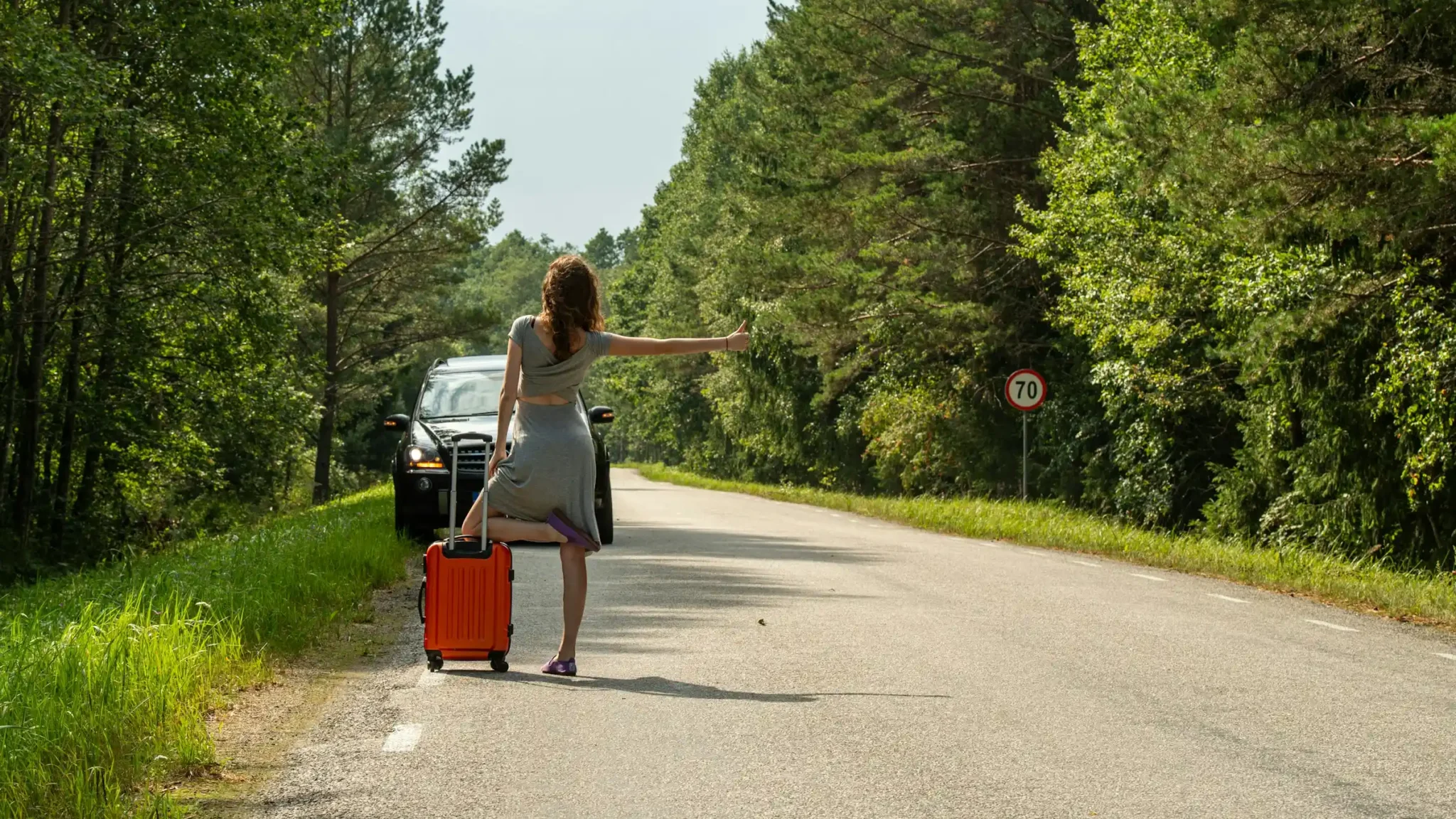 Woman traveling alone with a suitcase on a countryside road