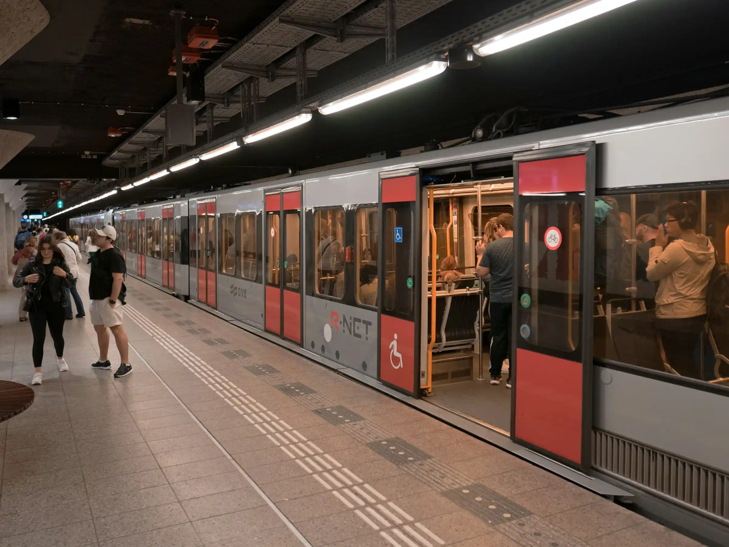 A modern Amsterdam metro train at a clean, bright underground station