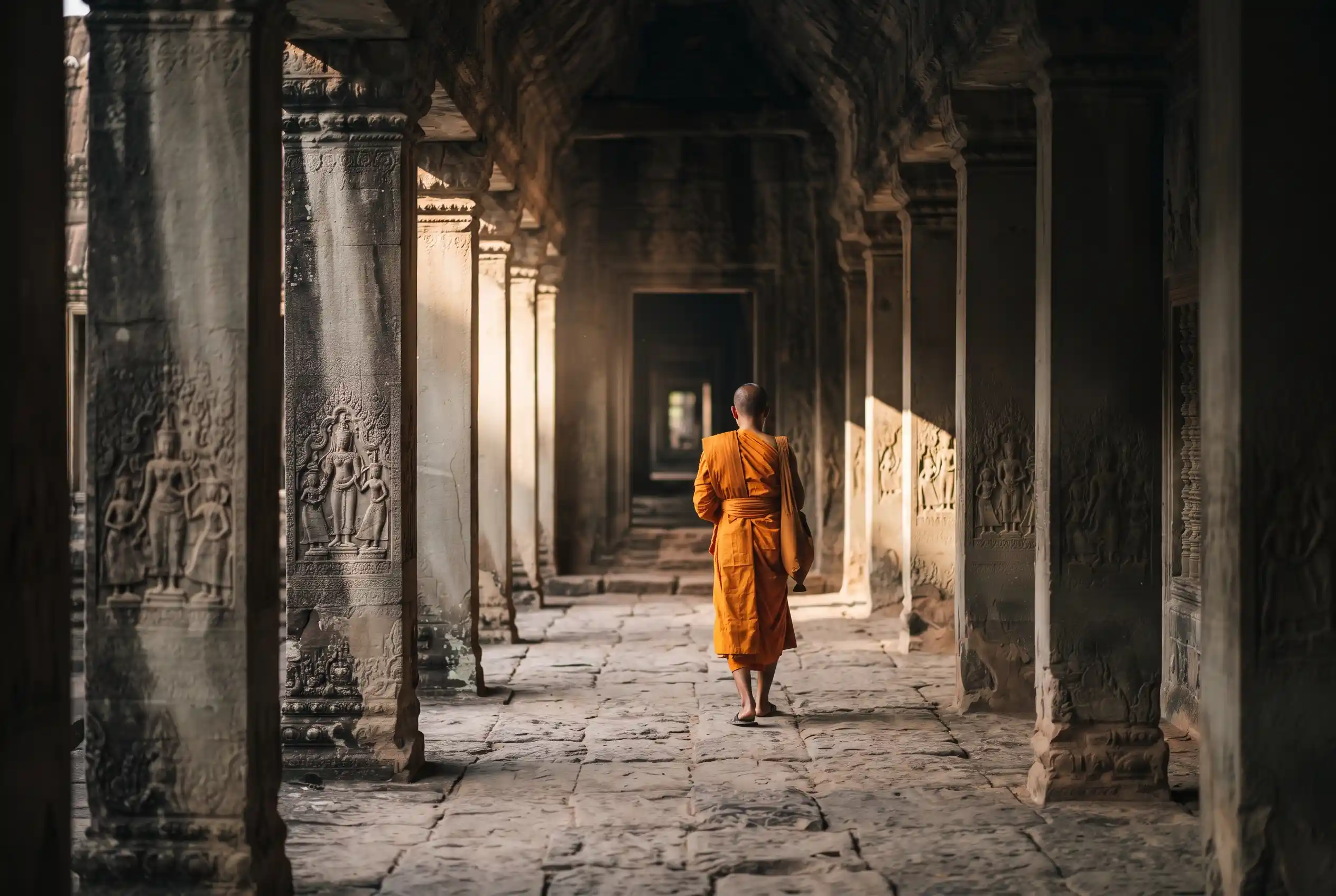 A Buddhist monk walking a corridor at Angkor Wat