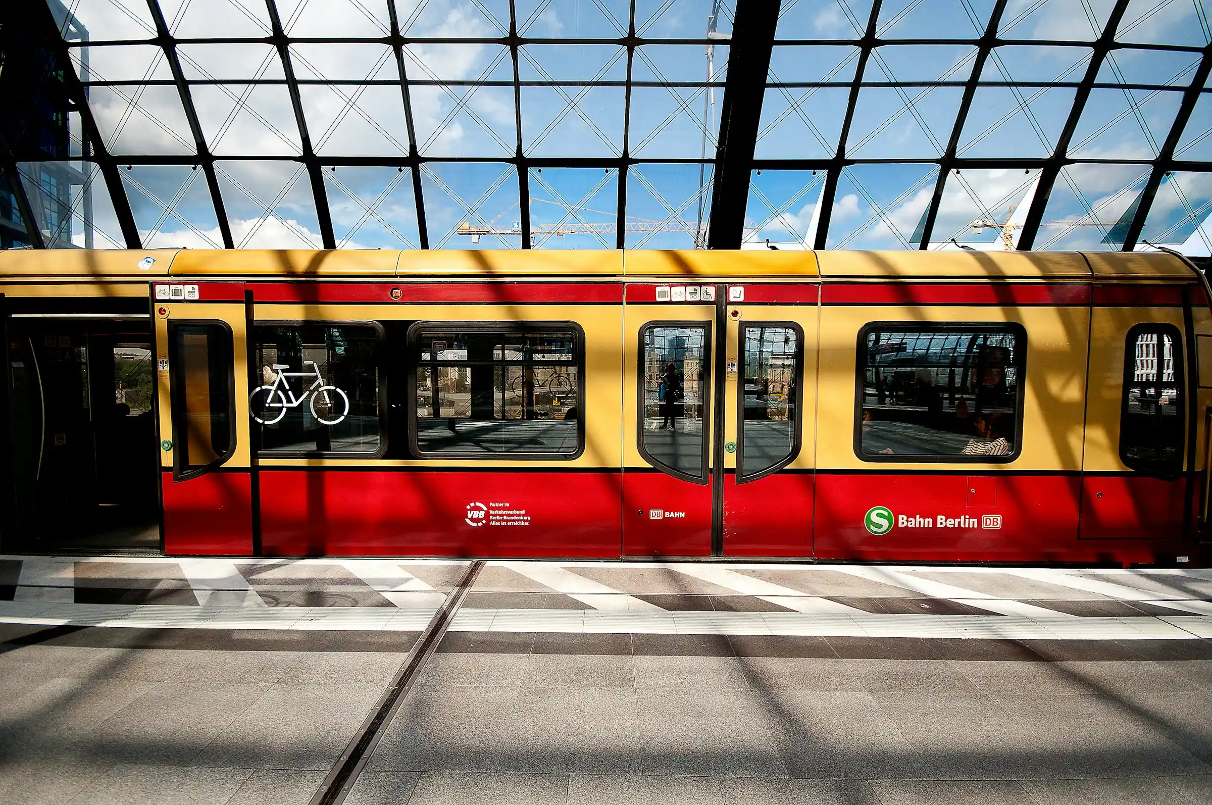 A yellow Berlin U-Bahn train arriving at an elevated station
