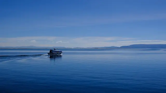 Sandy shoreline of Lake Titicaca near Copacabana with blue water and distant mountains