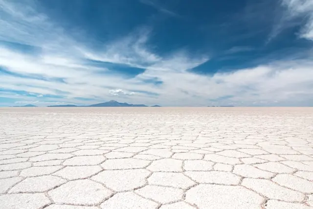 The Salar de Uyuni salt flat in dry season showing the geometric hexagonal salt crust stretching to the horizon