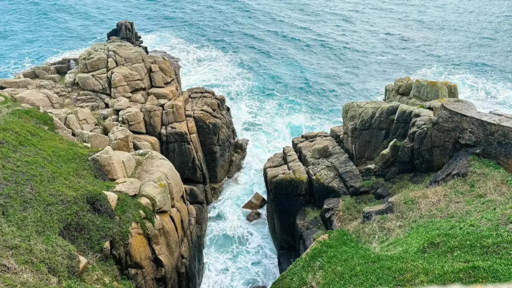 White sand and clear water at Porthcurno beach below the cliffs