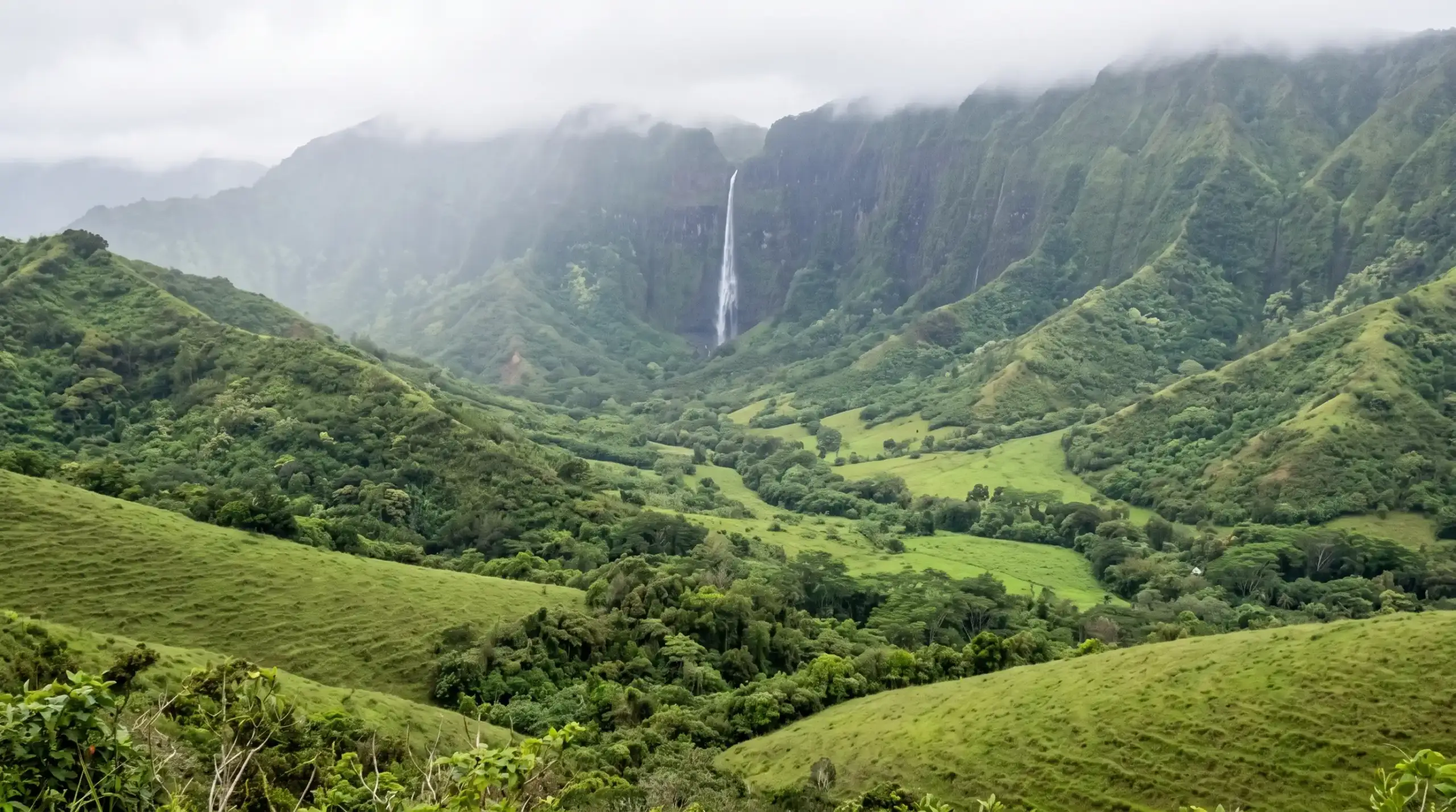 Lush green hiking trail through Oahu jungle with waterfall in the distance