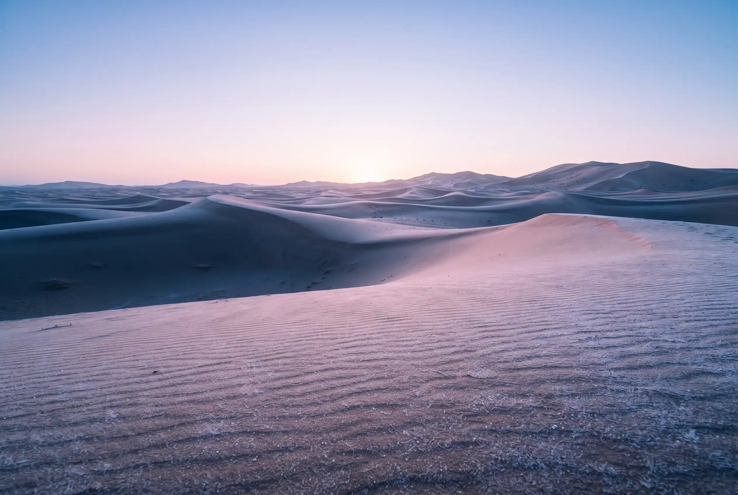 A cold clear winter dawn over Sahara dunes with frost on the sand