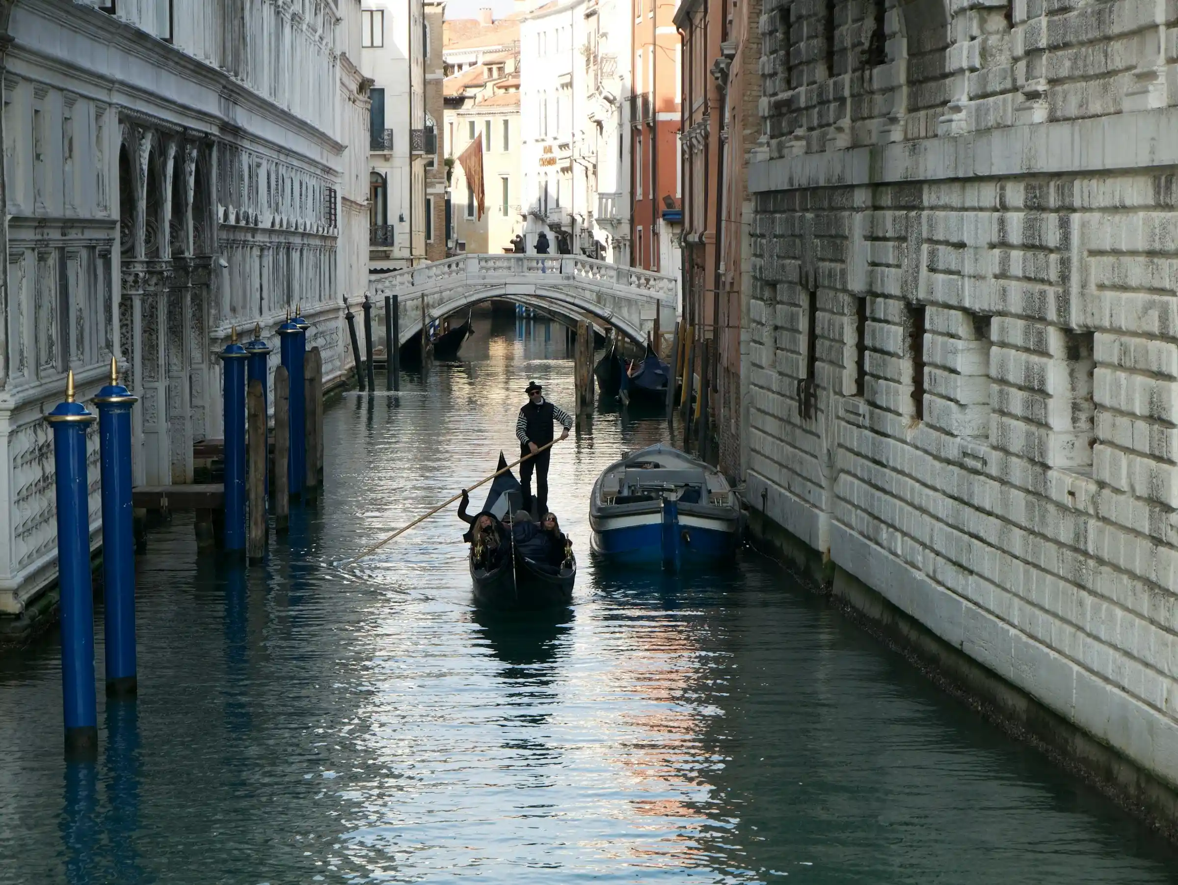 A small quiet stone bridge over a narrow Venice canal lined with old houses